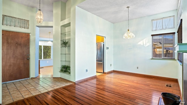 entrance foyer with a notable chandelier, a high ceiling, a textured ceiling, and light wood-type flooring