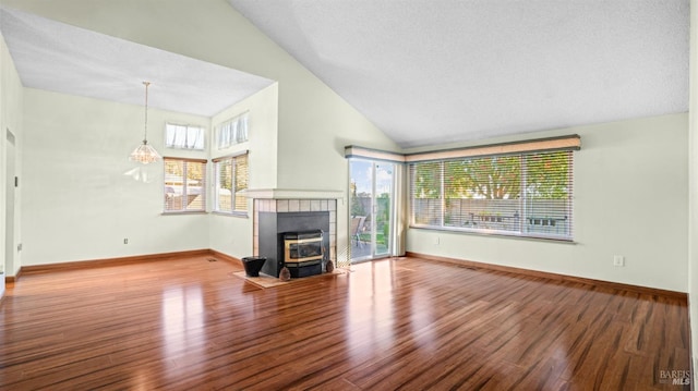 unfurnished living room featuring hardwood / wood-style flooring, lofted ceiling, a healthy amount of sunlight, and an inviting chandelier