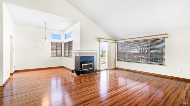 unfurnished living room featuring high vaulted ceiling, baseboards, a chandelier, and wood finished floors