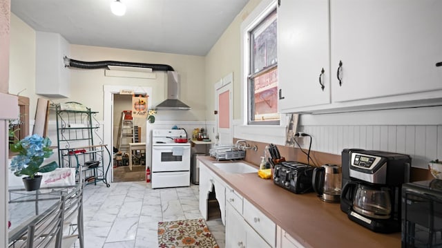 14090 Winnie St, Walnut Grove, CA 95690 - kitchen featuring white electric stove, wall chimney exhaust hood, light marble finish flooring, white cabinets, and wainscoting