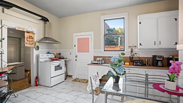 14090 Winnie St, Walnut Grove, CA 95690 - kitchen with white electric range oven, wall chimney exhaust hood, light marble finish flooring, a wainscoted wall, and white cabinetry