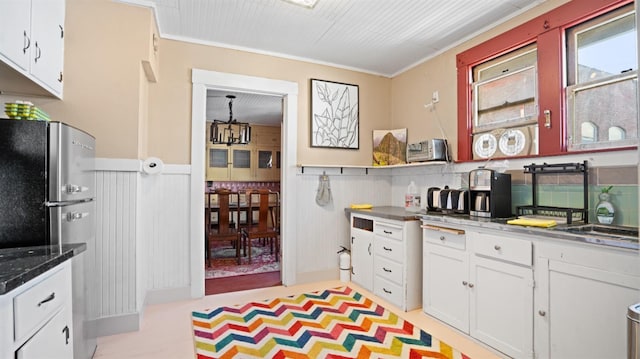 14090 Winnie St, Walnut Grove, CA 95690 - kitchen with freestanding refrigerator, a wainscoted wall, white cabinetry, and crown molding