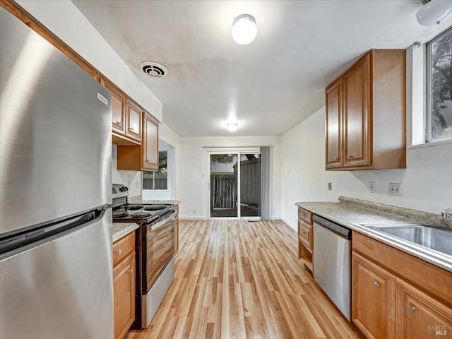 kitchen with sink, stainless steel appliances, and light wood-type flooring