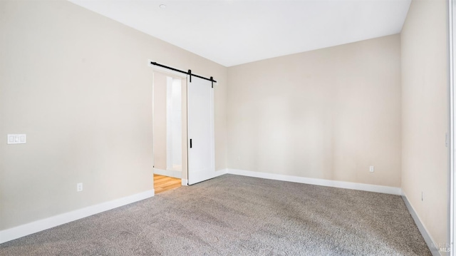 spare room featuring carpet and a barn door