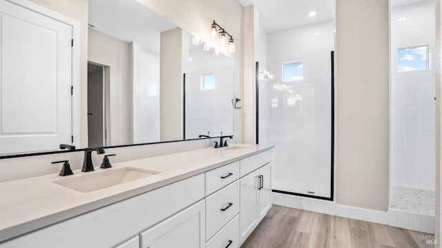 bathroom with vanity, tiled shower, wood-type flooring, and a healthy amount of sunlight