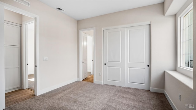 unfurnished bedroom with a closet and light colored carpet