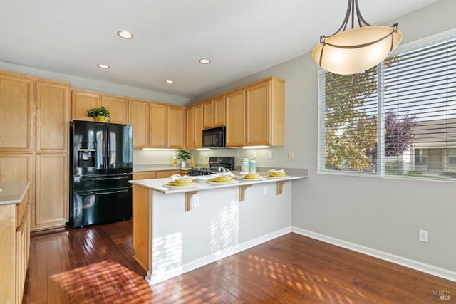 kitchen with dark wood-type flooring, black appliances, decorative light fixtures, and kitchen peninsula