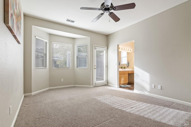 unfurnished bedroom featuring ensuite bathroom, light colored carpet, and ceiling fan