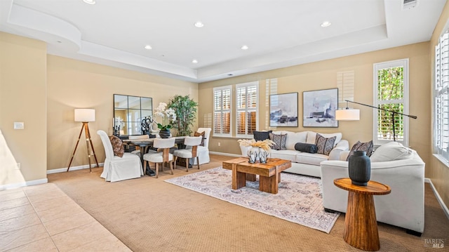 tiled living room featuring a healthy amount of sunlight and a tray ceiling