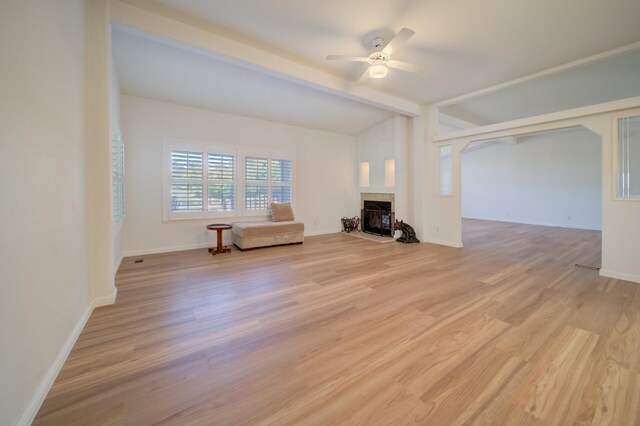 unfurnished living room featuring ceiling fan, vaulted ceiling with beams, a fireplace, and light hardwood / wood-style floors