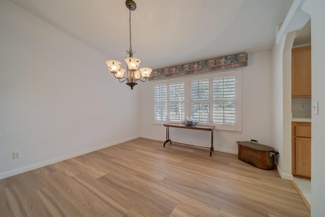 unfurnished dining area with a notable chandelier and light hardwood / wood-style flooring