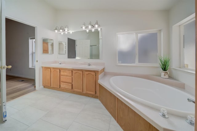 bathroom with tile patterned flooring, vanity, and a relaxing tiled tub