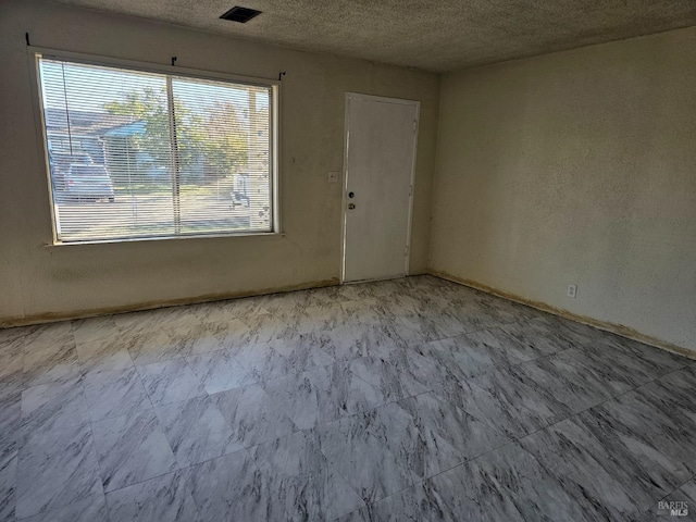 unfurnished room with visible vents and a textured ceiling