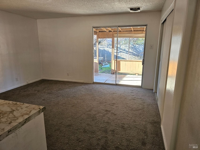 carpeted spare room featuring visible vents and a textured ceiling