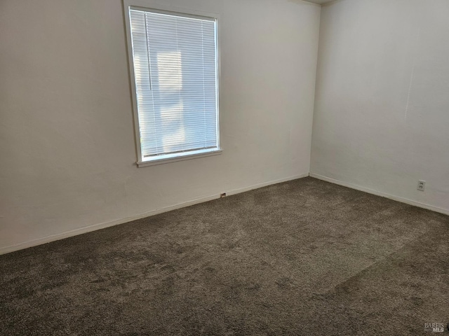 carpeted empty room featuring baseboards