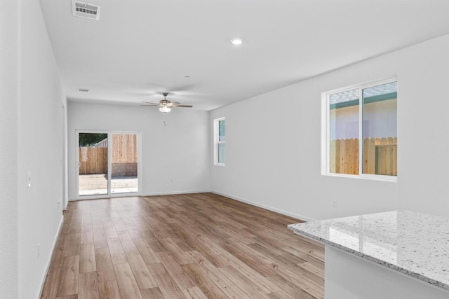 unfurnished living room featuring baseboards, a healthy amount of sunlight, visible vents, and light wood-style floors