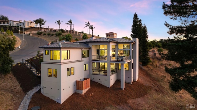 back house at dusk with a balcony