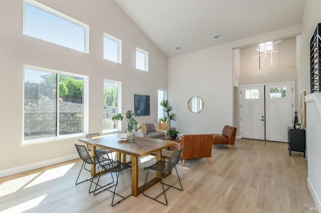 dining room with light hardwood / wood-style floors and high vaulted ceiling