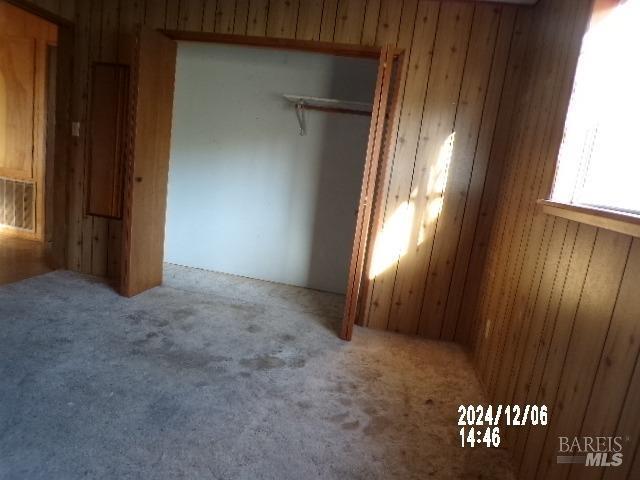 unfurnished bedroom with wood walls, a closet, and carpet floors