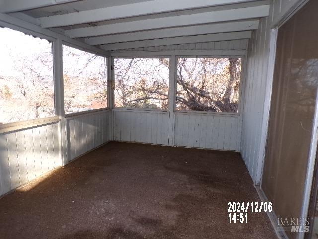 unfurnished sunroom with beam ceiling