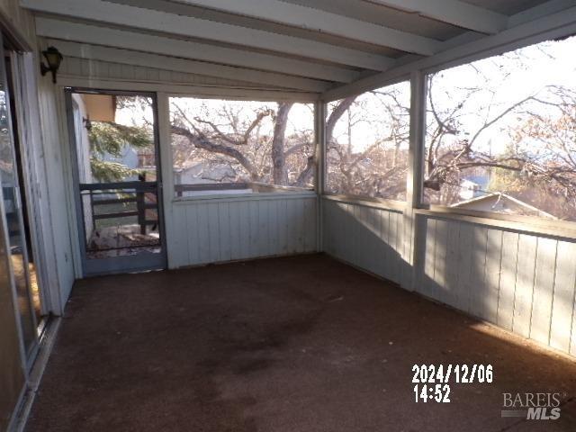 unfurnished sunroom with beam ceiling