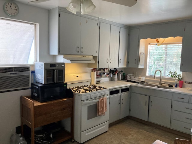 kitchen with a sink, under cabinet range hood, black microwave, light countertops, and white range with gas stovetop