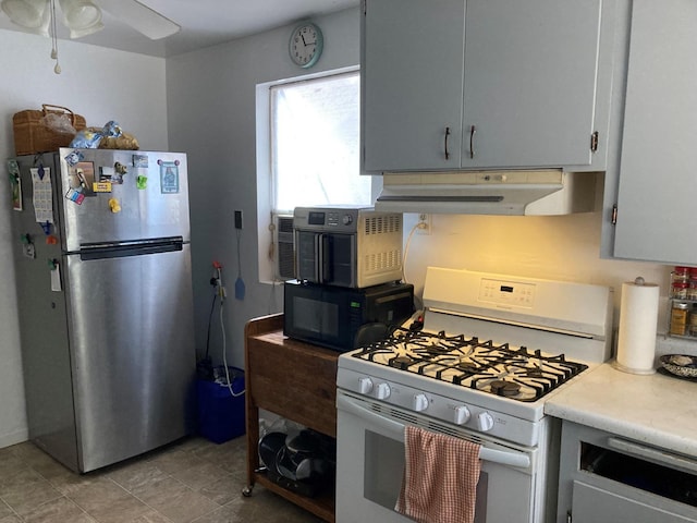 kitchen with black microwave, under cabinet range hood, light countertops, white range with gas cooktop, and freestanding refrigerator