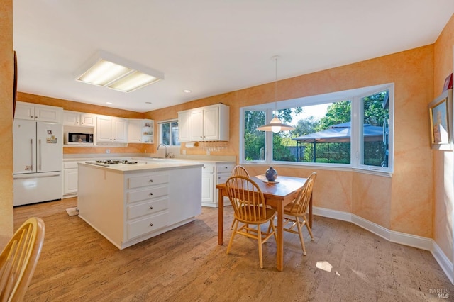 kitchen featuring light wood-type flooring, stainless steel appliances, pendant lighting, and white cabinets