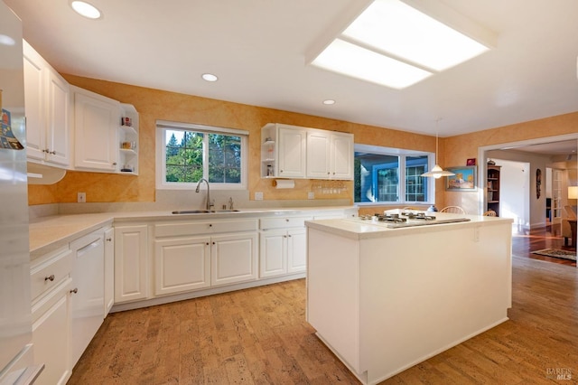 kitchen featuring white cabinets, light hardwood / wood-style flooring, pendant lighting, sink, and white appliances