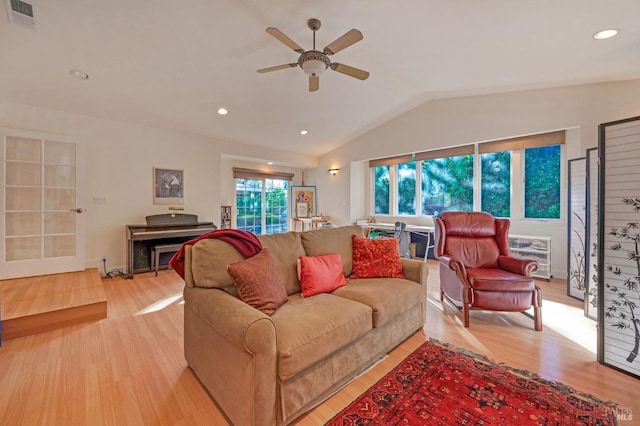 living room with lofted ceiling, heating unit, light wood-type flooring, and ceiling fan