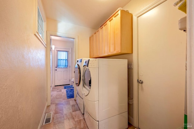 clothes washing area featuring cabinets and separate washer and dryer