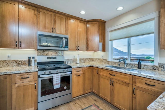 kitchen with light stone countertops, appliances with stainless steel finishes, and light hardwood / wood-style flooring