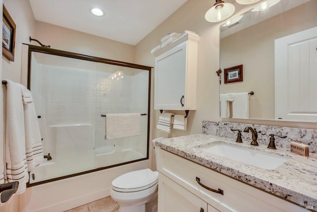 full bathroom with vanity, bath / shower combo with glass door, toilet, and tile patterned floors