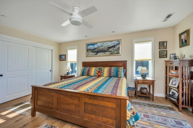 bedroom with a closet, ceiling fan, hardwood / wood-style flooring, and multiple windows