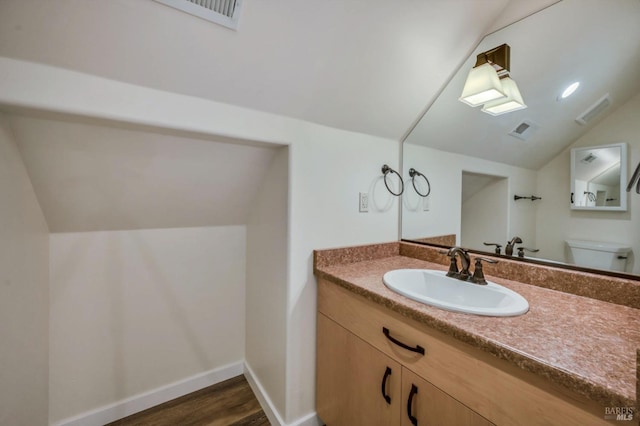 bathroom featuring vanity, toilet, wood-type flooring, and lofted ceiling