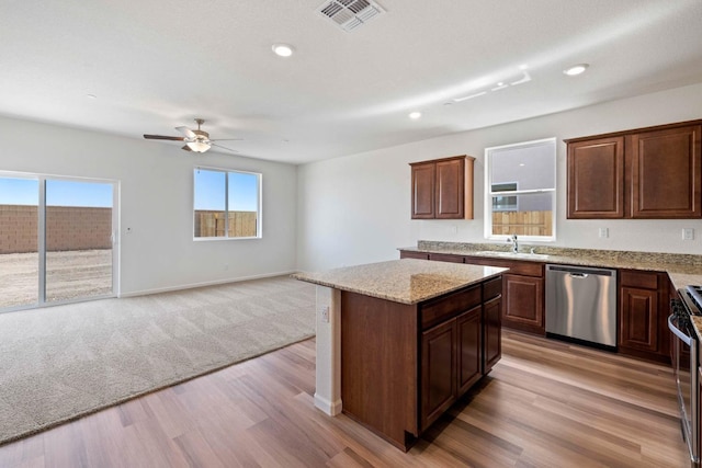 kitchen featuring light wood finished floors, visible vents, appliances with stainless steel finishes, open floor plan, and a sink