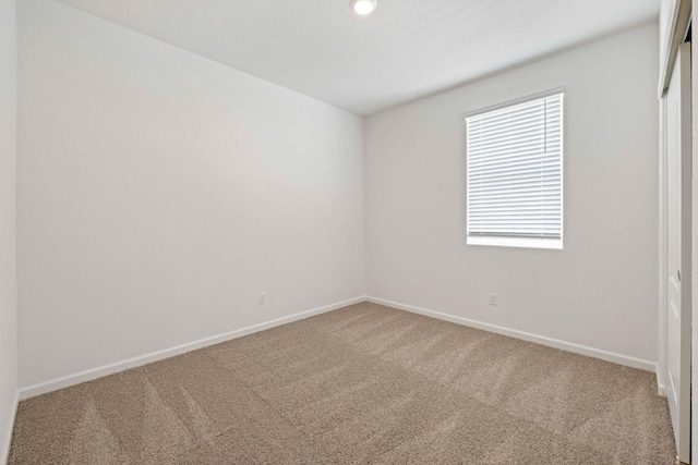 carpeted spare room featuring baseboards