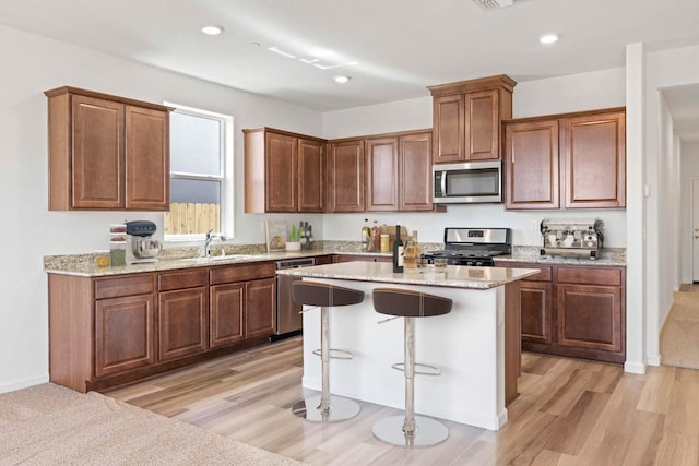 kitchen featuring a kitchen island, appliances with stainless steel finishes, a breakfast bar area, and recessed lighting