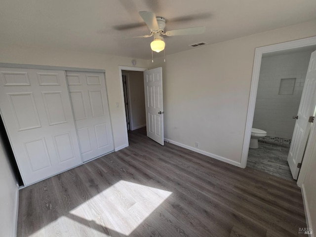 unfurnished bedroom featuring dark wood-type flooring, ceiling fan, connected bathroom, and a closet