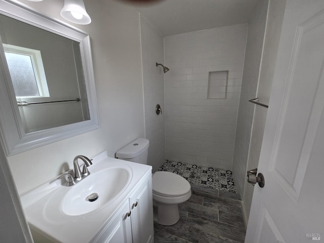 bathroom with vanity, tiled shower, and toilet