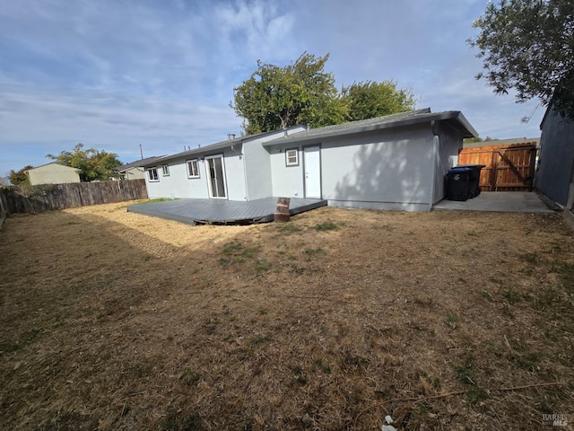 back of property featuring a lawn and a deck