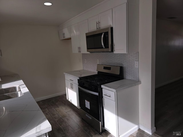 kitchen with sink, appliances with stainless steel finishes, white cabinetry, backsplash, and light stone counters