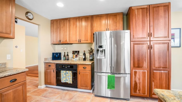 kitchen featuring light tile patterned flooring, oven, light stone counters, and stainless steel fridge with ice dispenser