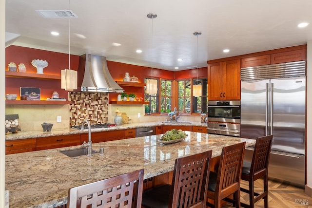 kitchen featuring island range hood, a breakfast bar area, pendant lighting, appliances with stainless steel finishes, and light stone counters