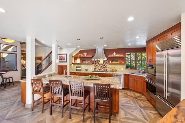 kitchen featuring hanging light fixtures, appliances with stainless steel finishes, light parquet floors, island range hood, and sink