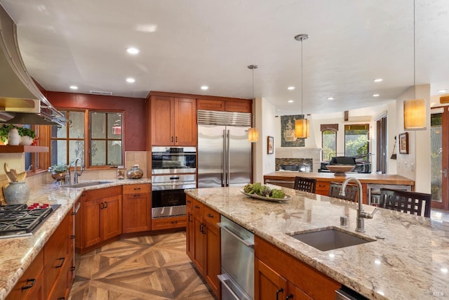 kitchen featuring parquet flooring, sink, appliances with stainless steel finishes, and light stone countertops