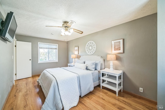 bedroom with light wood-type flooring, a ceiling fan, and a textured ceiling