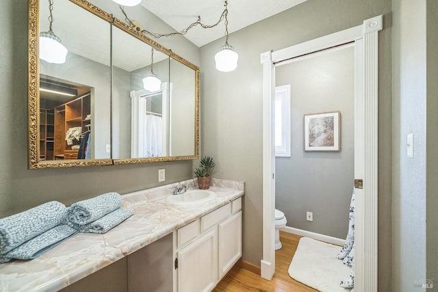 full bathroom with baseboards, vanity, toilet, and wood finished floors