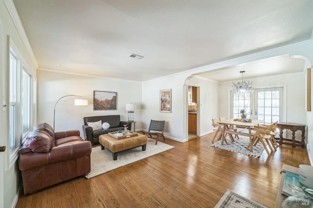 living room with hardwood / wood-style floors, ornamental molding, and an inviting chandelier