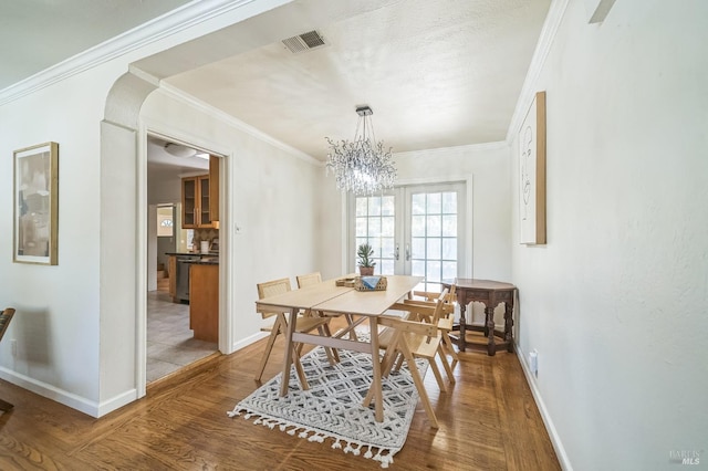 dining space with arched walkways, wood finished floors, visible vents, and baseboards